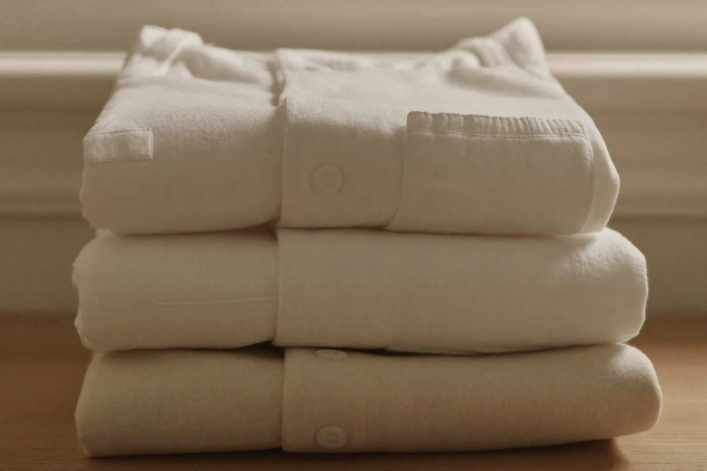 Pile de vêtements pour bébé en coton blanc et écru, produits concernés par la classe 1 du label Oeko-Tex