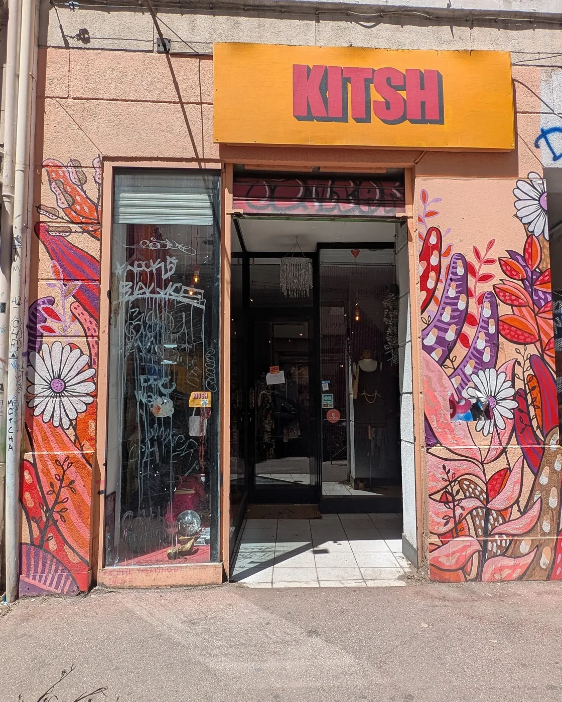 La devanture de Kitsh Vintage au 4 rue Fontange à Marseille, enseigne orange et encadrement peint de fleurs, à deux minutes du métro Notre-Dame-du-Mont