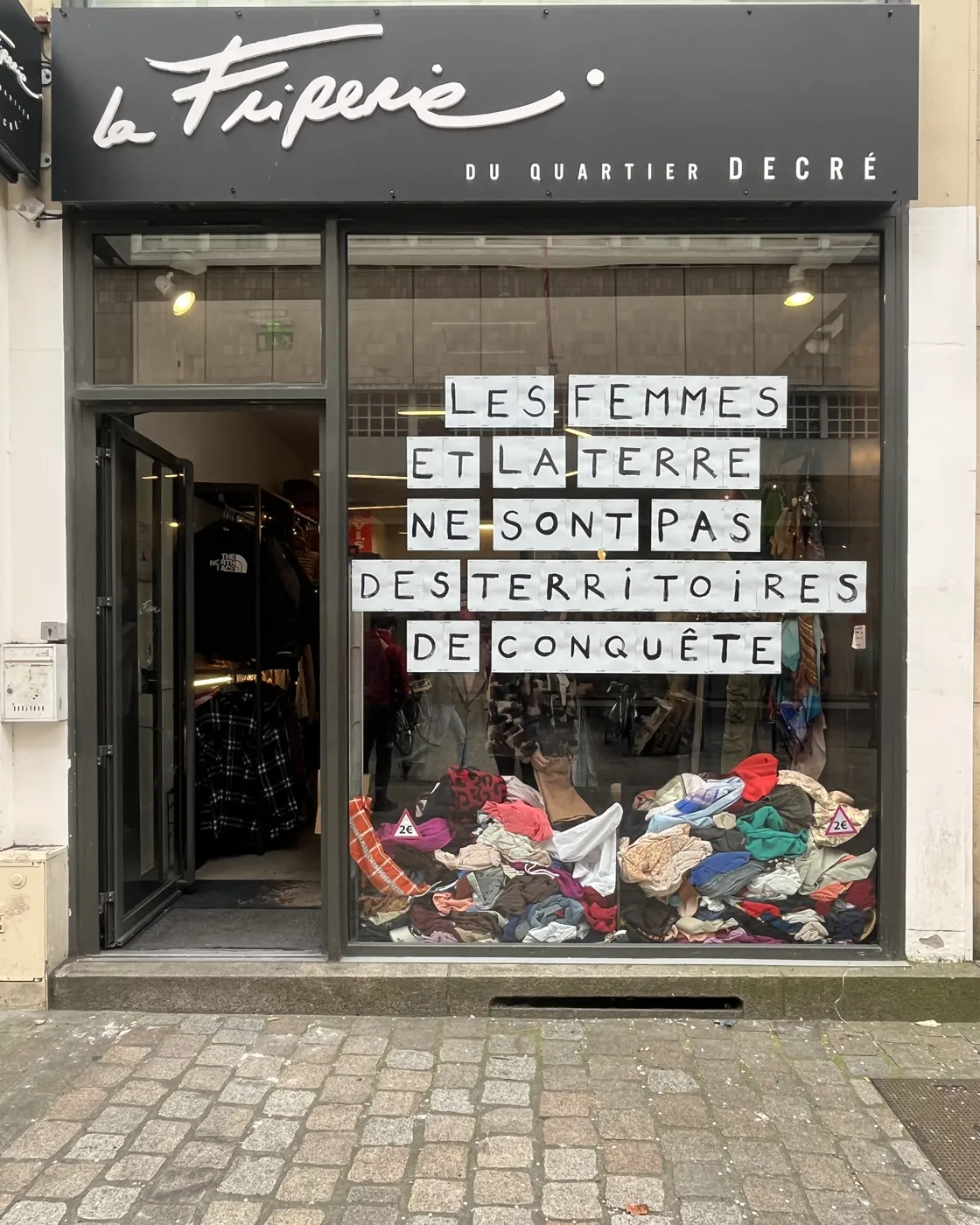 La vitrine de La Friperie du quartier Decré, 17 rue de la Marne à Nantes, avec des piles de vêtements à 2 euros derrière la vitre
