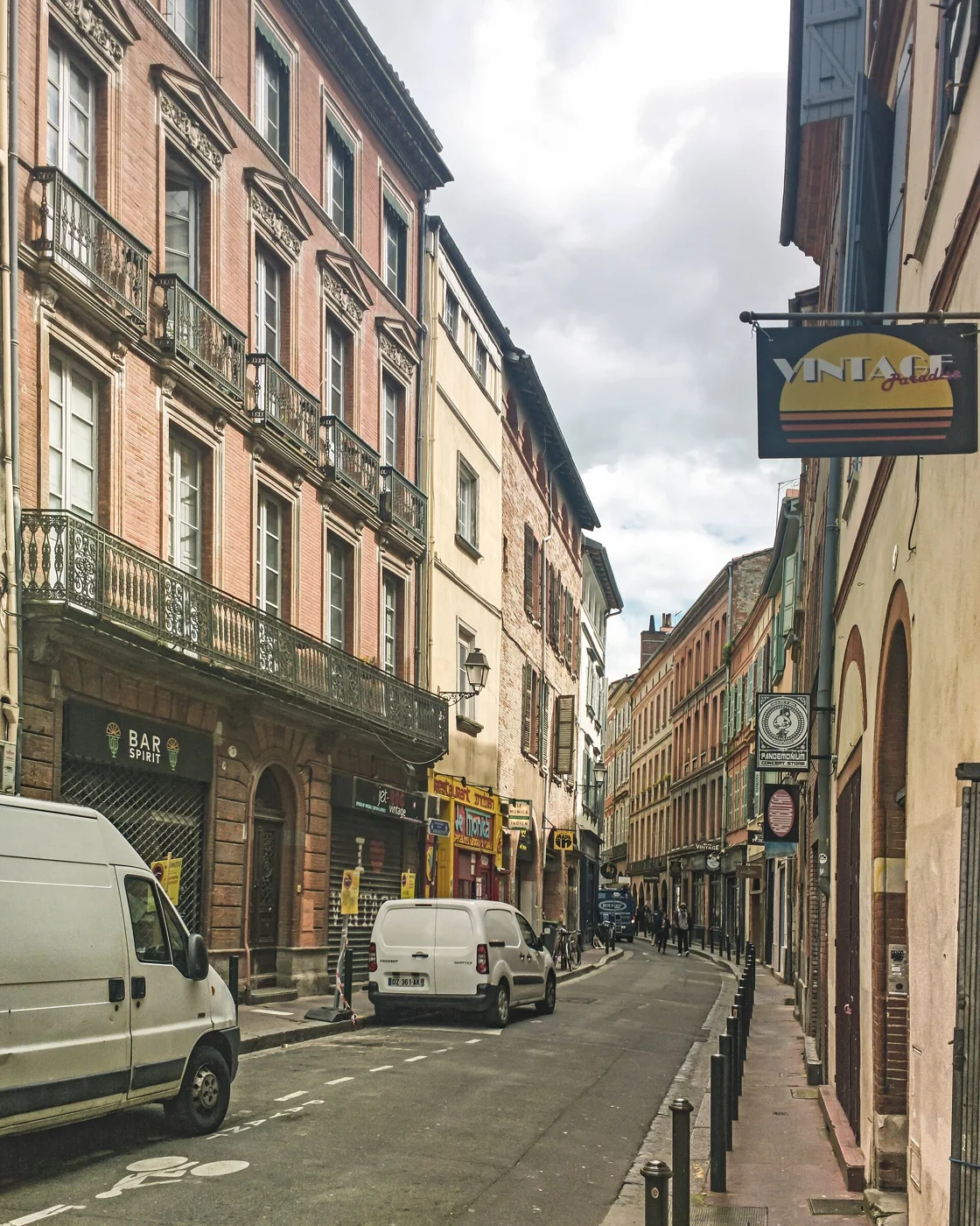L'enseigne suspendue de Vintage Paradise dans la rue Cujas à Toulouse, rue étroite de briques qui aligne trois friperies de vintage américain entre Esquirol et la Daurade