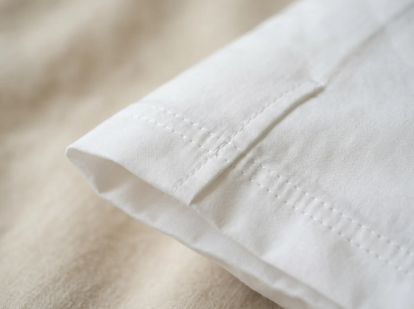 Détail de l'ourlet piqué d'une housse de couette en percale de coton blanche, surpiqûre régulière au fil blanc