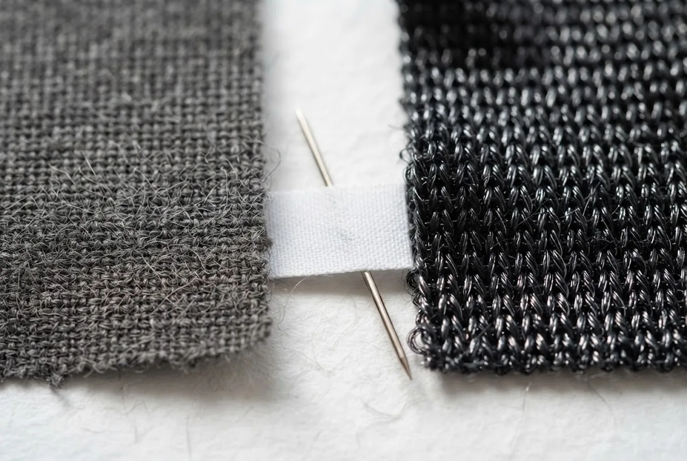 Deux échantillons de tissu côte à côte : une maille mate et pelucheuse à gauche, une maille de polyamide noire et brillante à droite, séparées par une étiquette de composition vierge